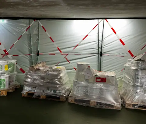 Paletten mit Beschichtungsmaterial stehen im abgesperrten Baustellenbereich einer Tiefgarage bereit.