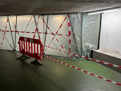 Abgesperrter Bauabschnitt in einer Tiefgarage mit dem alten, abgenutzten grünen Bodenbelag vor der Sanierung.