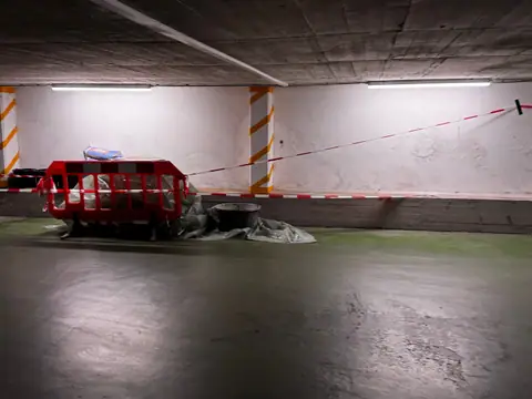 Fahrgasse einer Tiefgarage mit abgenutztem grünem Altbelag und Absperrgittern vor der Sanierung.