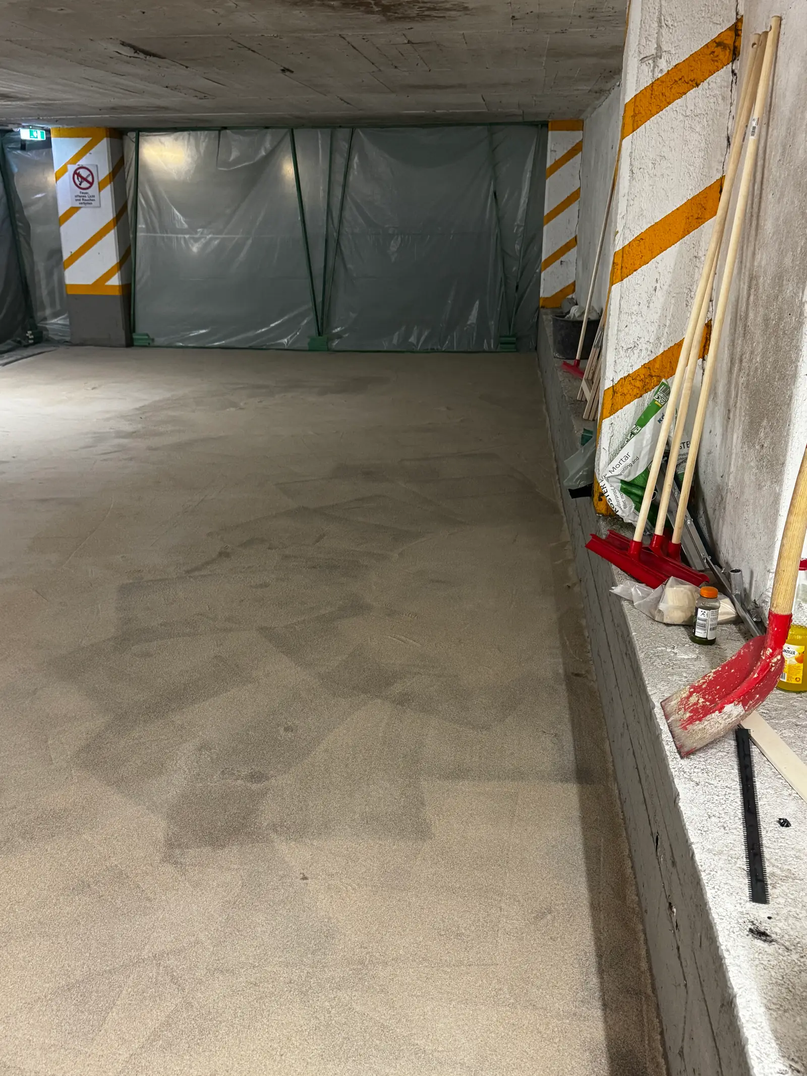 Grundierte Bodenfläche in einer Tiefgarage, mit Quarzsand abgestreut. Diese Schicht sorgt für Haftung und Rutschfestigkeit.