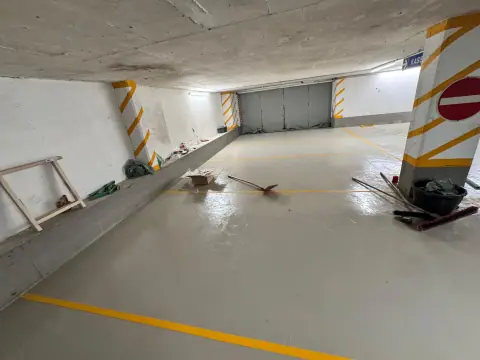 Fertig beschichteter Fahrweg in einer Tiefgarage: heller grauer Boden mit gelben Markierungslinien.