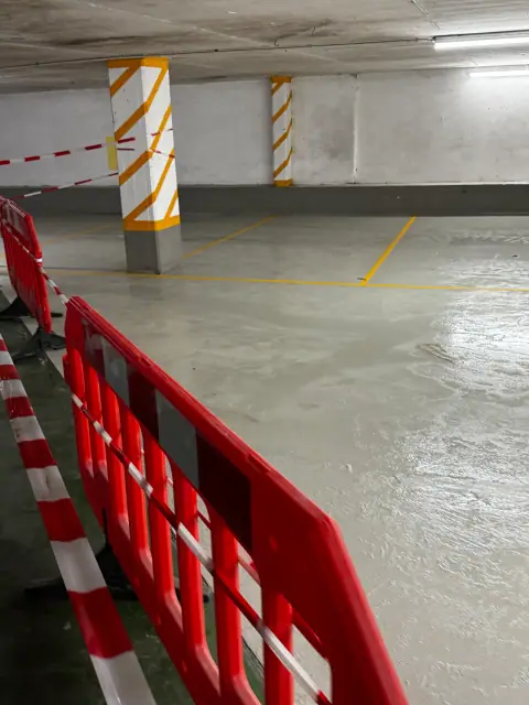Derselbe Stellplatzbereich mit fertiger grauer Bodenbeschichtung und neuen Markierungen, noch abgesperrt zum Aushärten.