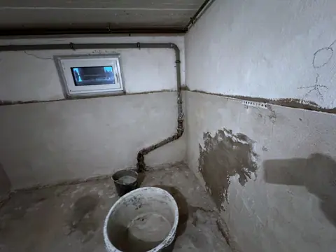 Dieselbe Kellerecke mit frischem Sanierputz, ein Mörteleimer steht noch im Raum.