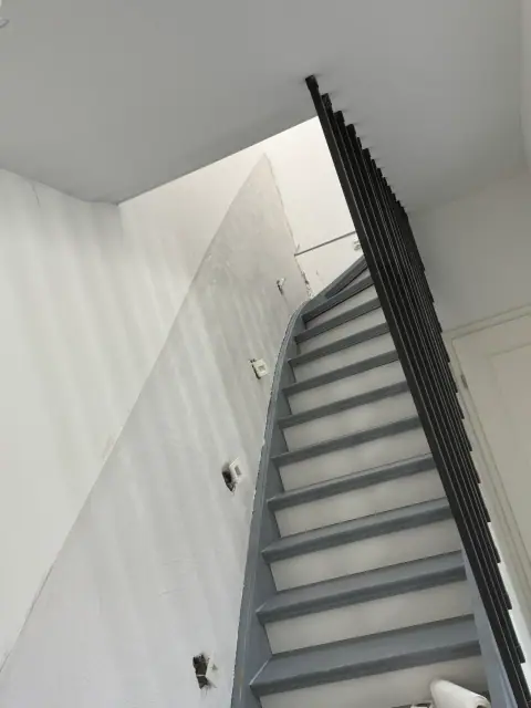 Dieselbe Treppenhauswand nach der Sanierung: glatt verputzt und gestrichen, keine Feuchtespuren mehr.